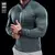 Camiseta esportiva masculina de manga comprida em tom verde, modelada por um homem com braços musculosos.