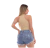 Modelo feminina usando shorts jeans rasgados e blusa de alças, mostrando a parte de trás do look.