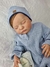 Bebê reborn super realista Lucca, vestindo um macacão azul e um gorro, com expressão serena e olhos fechados.