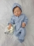 Bebê reborn super realista Lucca, vestido com macacão azul e gorro, segurando um pano.