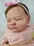 Bebê reborn super realista Bianca com vestido rosa e laço na cabeça.