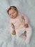 Bebê reborn super realista Bianca vestida com um macacão rosa, usando um laço na cabeça e segurando um chupeta dourada.