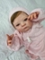 Bebê reborn super realista Anabel vestido com roupinha rosa e gorro, com expressão facial delicada e mãos pequenas.