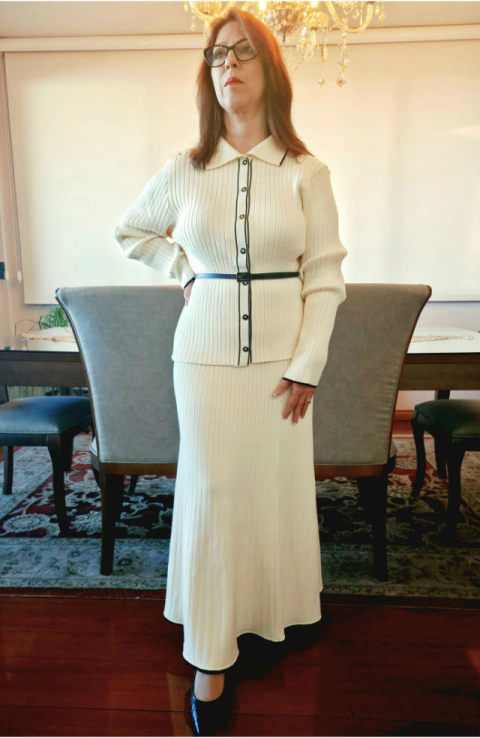 O conjunto é composto por casaqueto em malha de tricô com modelagem elegante e estruturada, gola estilo camisa, mangas compridas e fechamento frontal por botões, proporcionando um visual sofisticado e atemporal. A saia possui cós largo que valoriza a silh