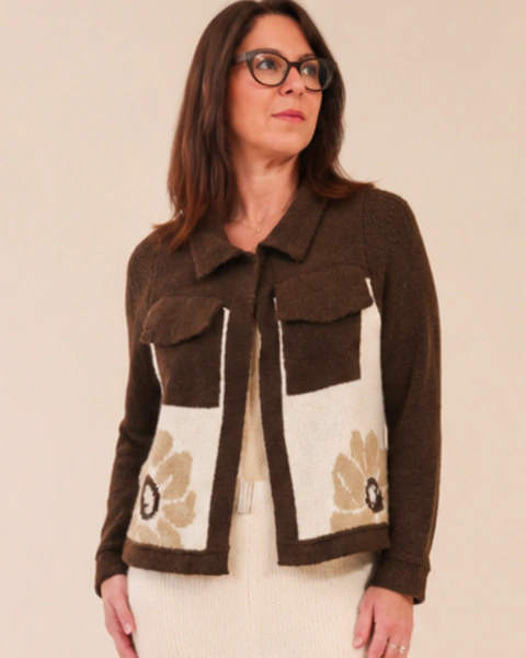 Casaco feminino de tricô em jacquard nas cores marrom, bege e branco, com flores em tons suaves, bolsos frontais e comprimento na altura do quadril, perfeito para compor looks casuais e versáteis. Vai bem com jeans, vestidos ou até sobreposto.