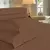 Colcha porta travesseiro em tom de marrom com textura, composta por três peças, sobre uma cama.