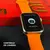 Smartwatch WS25 Mini 42mm com tela mostrando a função de controle de câmera, com pulseira laranja em fundo vermelho.