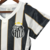 Camisa de torcedor feminina do Santos, branca e preta, com detalhes em dourado e escudo do clube.