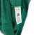 Etiqueta de um produto de vestuário verde com informações sobre cuidados e fabricação.