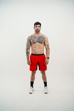 Homem com tatuagens usando shorts vermelhos tijolo da marca Lurk.