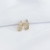 Brinco gota em ouro amarelo 18K, vazado e cravejado com zircônia, sobre fundo branco.