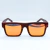 Óculos Decck polarizado com armação em madeira fake e lentes laranjas.
