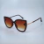 Óculos de sol marrom com formato estilizado e lentes degradê.