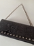 Cartera sobre negro con tachas