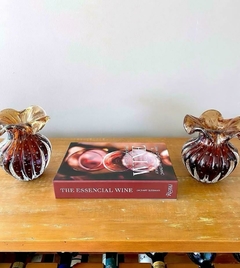 Dois vasos de vidro marrons em cima de uma mesa com um livro sobre vinho ao centro.