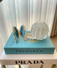 Livro caixa Prada grande com capa branca e detalhes em preto, apresentando o título "PRADA" e a palavra "CATWALK" e borboleta de ágata azul e murano