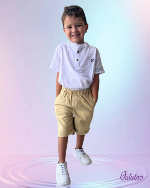 Criança sorridente usando uma camisa social infantil branca com botão e calças curtas bege.