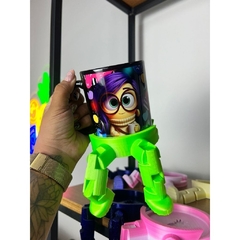 Caneca colorida com personagem animado e suporte verde em formato de pernas.