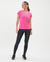 Modelo usando uma camisa feminina dry fit poliamida rosa, combinada com leggings escuras e tênis, em um fundo claro.