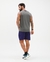 Homem de costas usando um short masculino oversized azul e camiseta sem mangas cinza, com tênis esportivos.