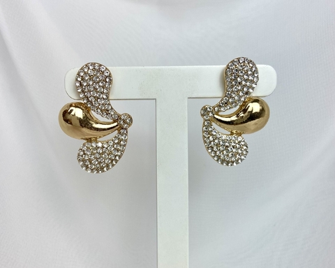 Brinco com strass em formato elegante, com detalhes dourados e brilhantes, exposto em um suporte branco.