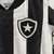 Detalhe do uniforme infantil do Botafogo, mostrando o escudo em preto e branco e a textura da camiseta.