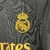 Emblema do Real Madrid em um kit infantil preto com detalhes em amarelo da Adidas.