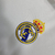 Logo bordado do Real Madrid em um kit infantil branco com detalhes em dourado.