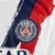 Logo do Paris Saint-Germain em um kit infantil branco da Nike, com detalhes em vermelho e azul.