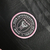 Emblema do Kit Infantil Inter Miami I 24/25 da Adidas, com fundo preto e detalhes em rosa.