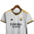 Camisa infantil do Real Madrid, modelo branco da Adidas, temporada 23/24, com detalhes em amarelo e logo do clube.