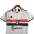 Camisa branca do Kit Infantil São Paulo I Adidas 23/24, com detalhes em vermelho e preto, pendurada em um cabide.