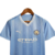 Camisa do kit infantil do Manchester City, modelo 23/24, na cor azul, com detalhes e logo do clube.