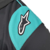 Detalhe da manga da camisa masculina Petronas 23/24 Fórmula 1, destacando o logotipo em preto e azul.