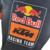 Detalhe da camisa masculina azul da Red Bull para a temporada de Fórmula 1 23/24, destacando o logotipo da equipe KTM Racing Team.