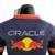 Camisa masculina da Red Bull para a temporada 23/24 da Fórmula 1, mostrando o logo da Oracle e os icônicos touros vermelhos.