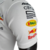 Detalhe da manga da camisa branca masculina da Red Bull 23/24 Fórmula 1, com logos de patrocinadores.