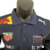 Camisa masculina azul da Red Bull para a temporada de Fórmula 1 23/24, com detalhes de patrocinadores e logotipos.