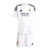 Kit infantil do Real Madrid para a temporada 2024/25, composto por camiseta e shorts brancos com detalhes em preto.