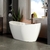 Banheira freestanding branca em banheiro moderno com plantas e decoração elegante.
