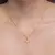 Colar mini cruz cravejada de zircônias banhado a ouro 18K na internet