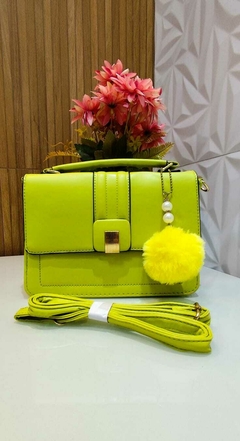 Bolsa feminina casual verde limão com pingente decorativo em pelúcia e corrente, acompanhada de alça.