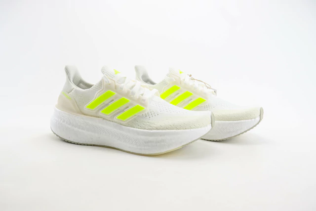 Tênis Adidas Ultraboost 5 na cor branca com detalhes em verde neon, exibindo design moderno e solado confortável disponível na Supernova Sneakers