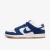 Tênis Nike SB Dunk Low nas cores azul e branco, com detalhes em camurça e solado de borracha.