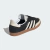 Imagem do tênis Adidas Samba "OG Core Black Wonder White" na cor preta, mostrando o detalhe traseiro e as listras brancas.