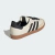 Tênis Adidas Samba na cor creme com detalhes em preto e sola marrom.