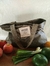 Bolsa para el mercado MUSGO de color gris claro, con asas, sobre una superficie de madera, rodeado de frutas y verduras frescas.