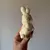 Vela en forma de conejo. El conejo tiene un diseño texturizado y un pequeño corazón en sus manos.