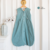 Saco de dormir verde para bebê, feito com 100% algodão, pendurado em cabide de madeira. ideal para noites amenas, proporciona conforto e segurança para o sono do bebê. TOG 2.0 

