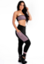 Modelo usando conjunto fitness com calça legging preta e cropped tomara que caia preto com detalhes em violeta.